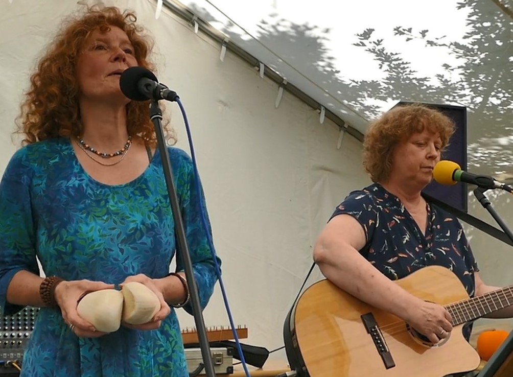 zwei Frauen mit Gitarre und Gesangsmikro